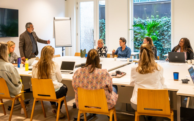 Trainer geeft uitleg aan medewerkers in trainingsruimte