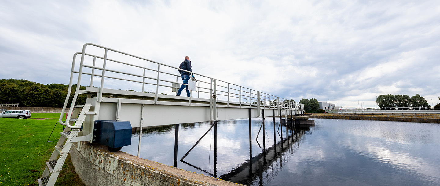 Medewerker loopt over een brug op waterzuivering